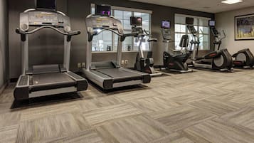 Een fitnessruimte met loopbanden, elliptische trainers en hometrainers.