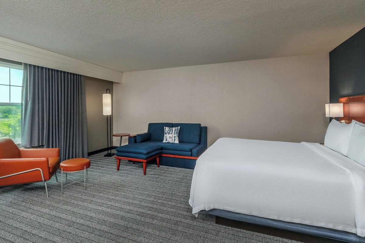 A hotel room with a bed, a sofa, a chair, and a small table.