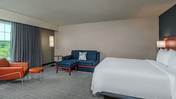 Una habitación de hotel con cama, sofá, sillón y una pequeña mesa.
