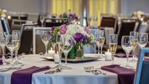 A dining table set with multiple wine glasses, a centerpiece with flowers, and candles. - Courtyard by Marriott Hadley Amherst (Hadley)