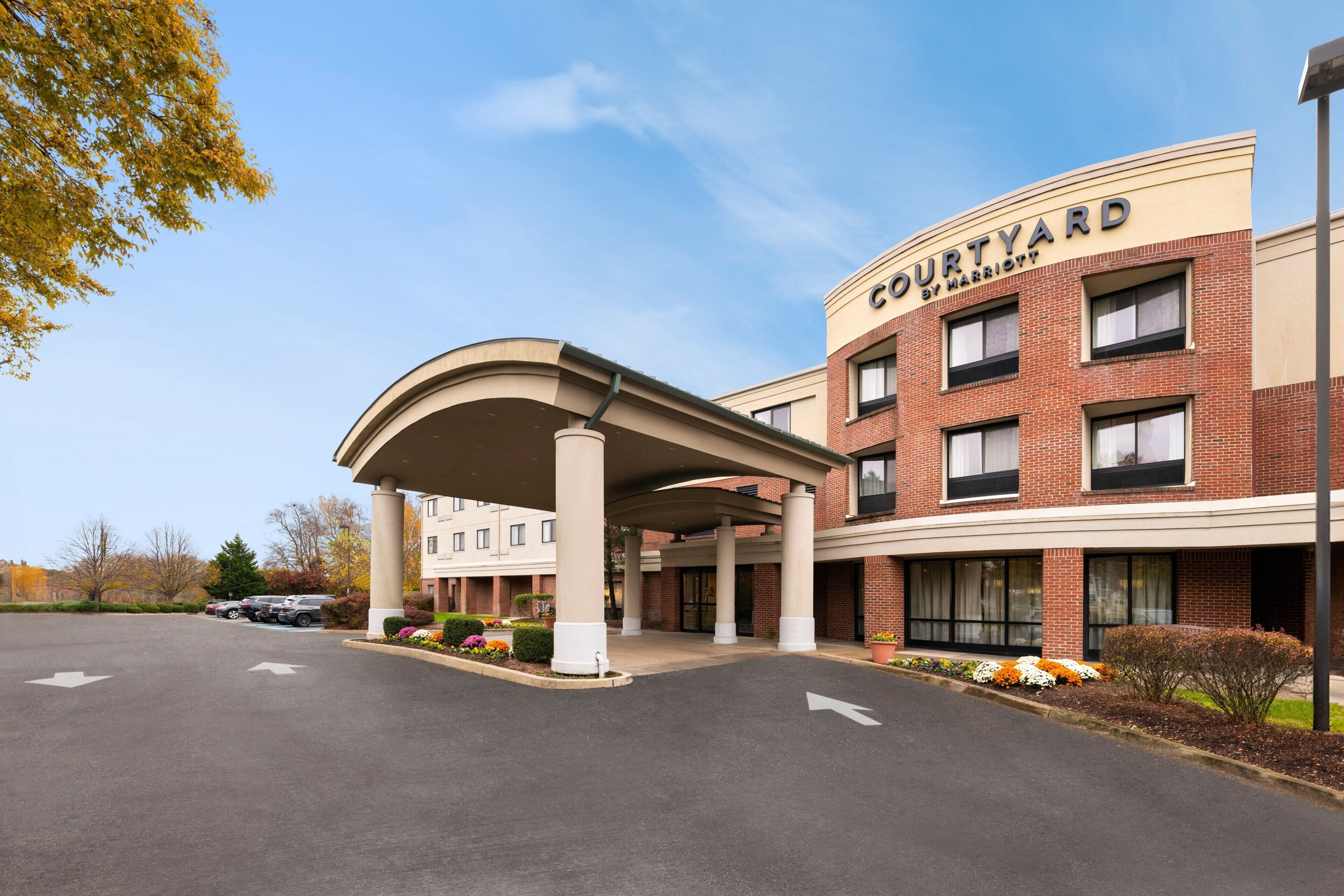 A Courtyard by Marriott hotel entrance with a covered walkway, brick facade, and a parking lot.