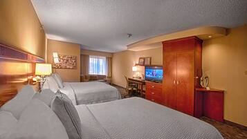 A hotel room with two beds, a desk, a television, and a wardrobe.