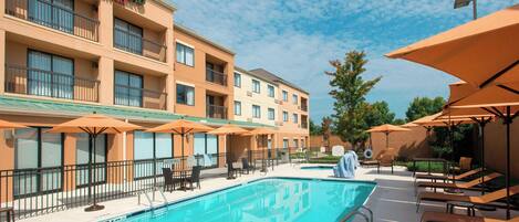 A hotel with a swimming pool, outdoor seating, and a Marriott sign.