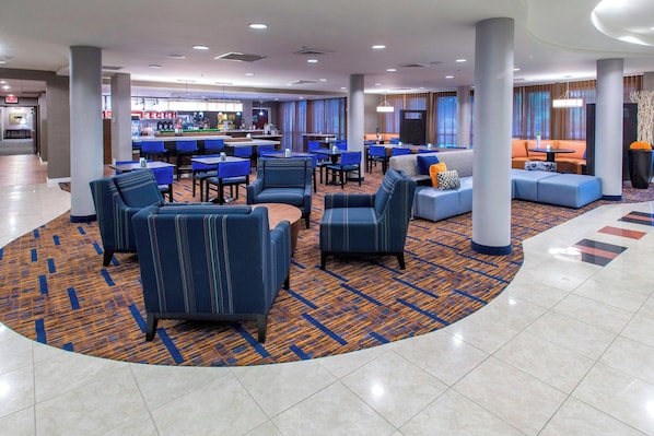 A hotel lobby with seating areas, a bar, and a reception desk.