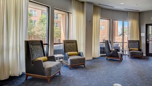 A hotel lobby with large windows, multiple chairs, and a patterned carpet.