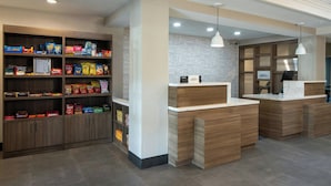 A reception area with wooden cabinets and a white counter, featuring a patterned wall and pendant lighting. - Fairfield Inn & Suites by Marriott Lafayette South (Lafayette)
