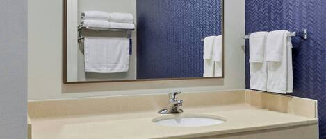 Un baño con un espejo grande, un lavabo y dos toalleros.