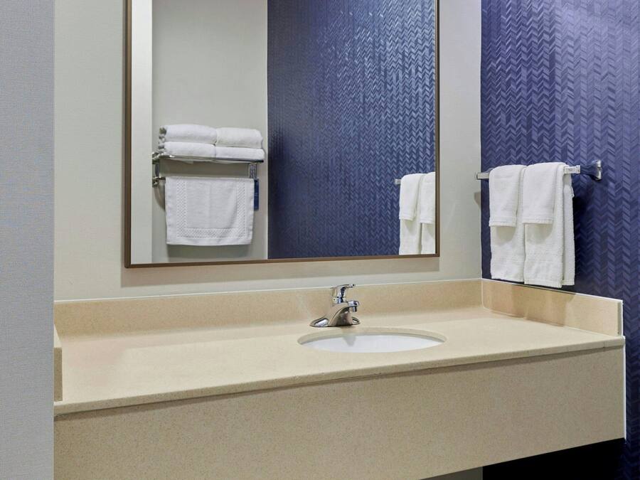 Un baño con un espejo grande, un lavabo y dos toalleros.