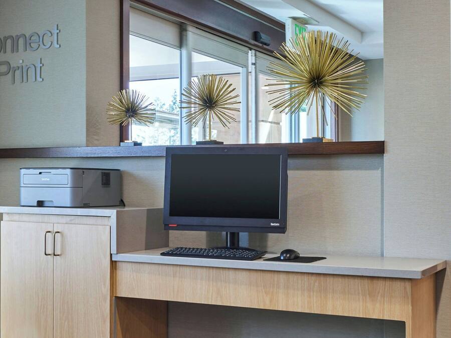 A modern office desk with a desktop computer, a printer, and a keyboard.