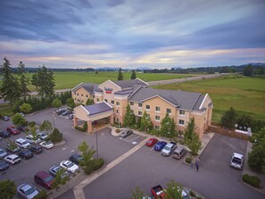 A hotel with a parking lot, a large building, and a view of the surrounding landscape. - Fairfield Inn & Suites by Marriott Burlington (Burlington)