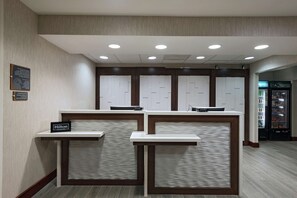 A hotel reception area with three counters, a sign reading "Hilton Honors," and a refrigerator in the background. - Homewood Suites by Hilton Fort Collins (Fort Collins)