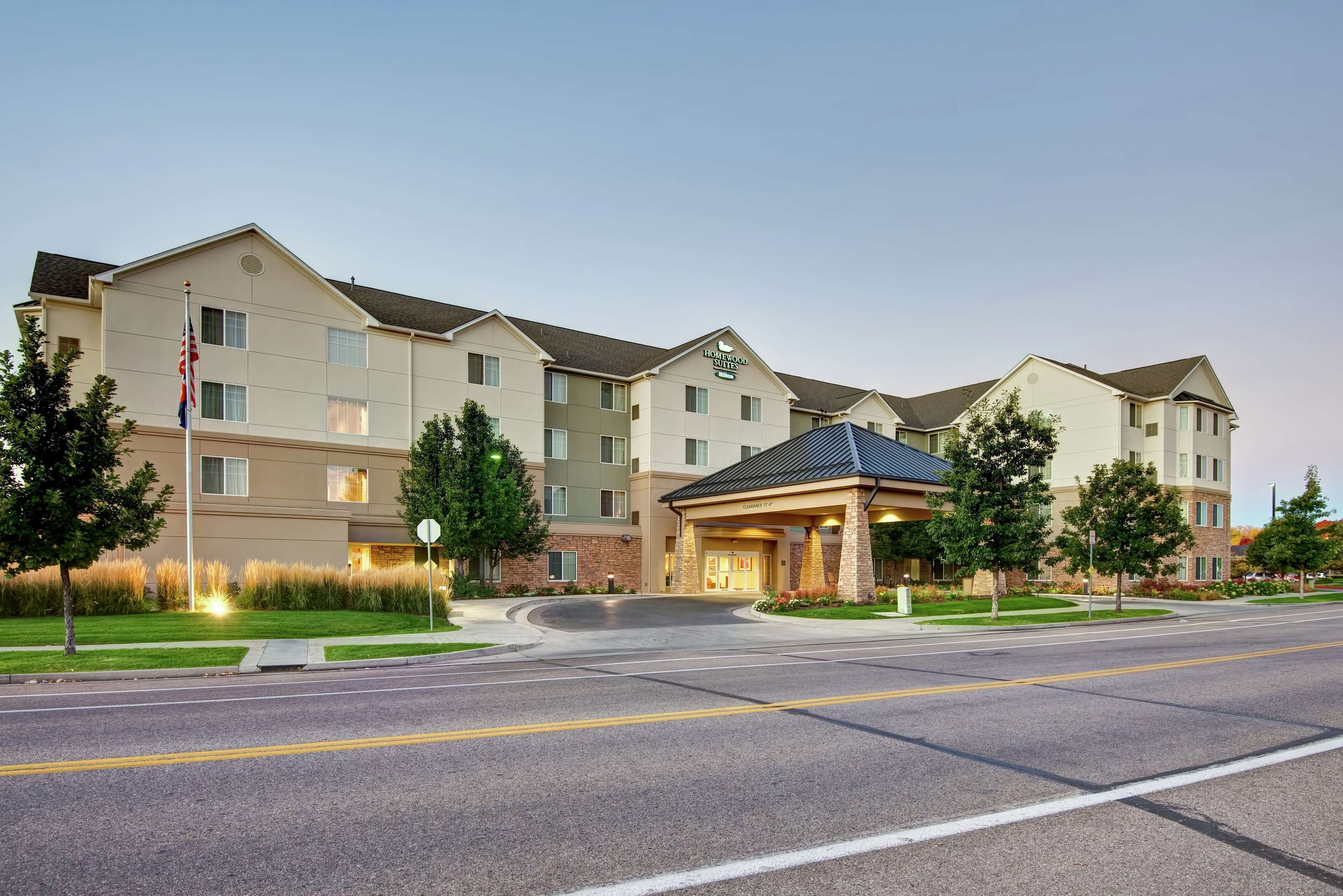 A multi-story hotel with a central entrance, a flagpole, and a landscaped front yard.