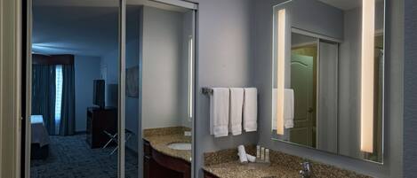 Een moderne badkamer met twee wastafels, een grote spiegel en een schuifdeur naar een slaapkamer.
