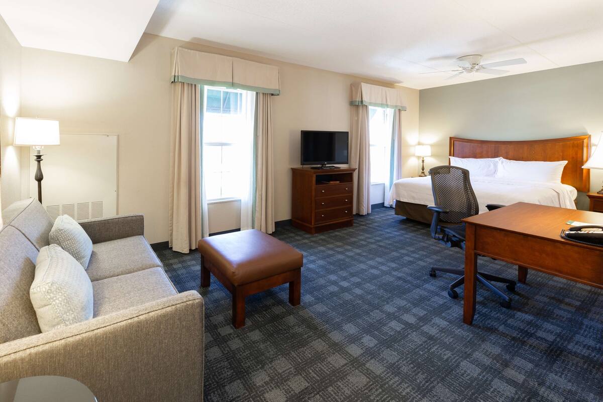 Une chambre d’hôtel équipée d’un lit, d’un bureau, d’une chaise, d’une télévision et d’un canapé.