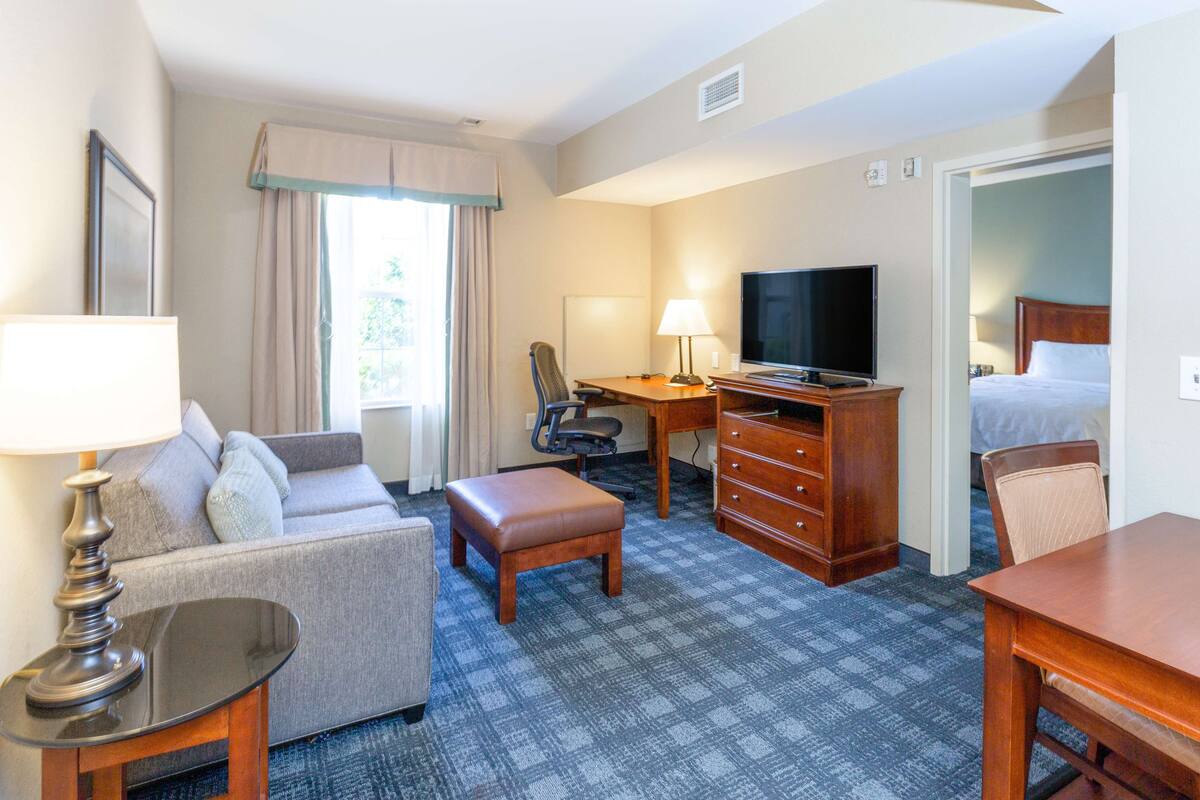 Une chambre d’hôtel équipée d’un canapé, d’un bureau, d’une télévision, d’une commode et d’un lit.