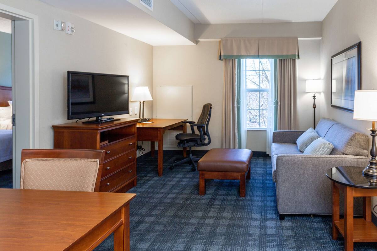 Une chambre d’hôtel comprenant un lit, un bureau avec une télévision, un canapé, une chaise, une table et une lampe.