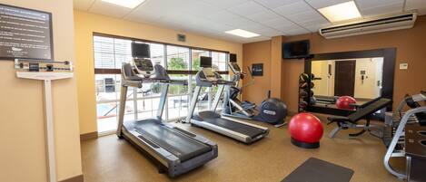 A gym with treadmills, exercise balls, and a mirror.