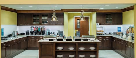 A spacious kitchen with wooden cabinets, a central island with multiple bowls, and various kitchen appliances.