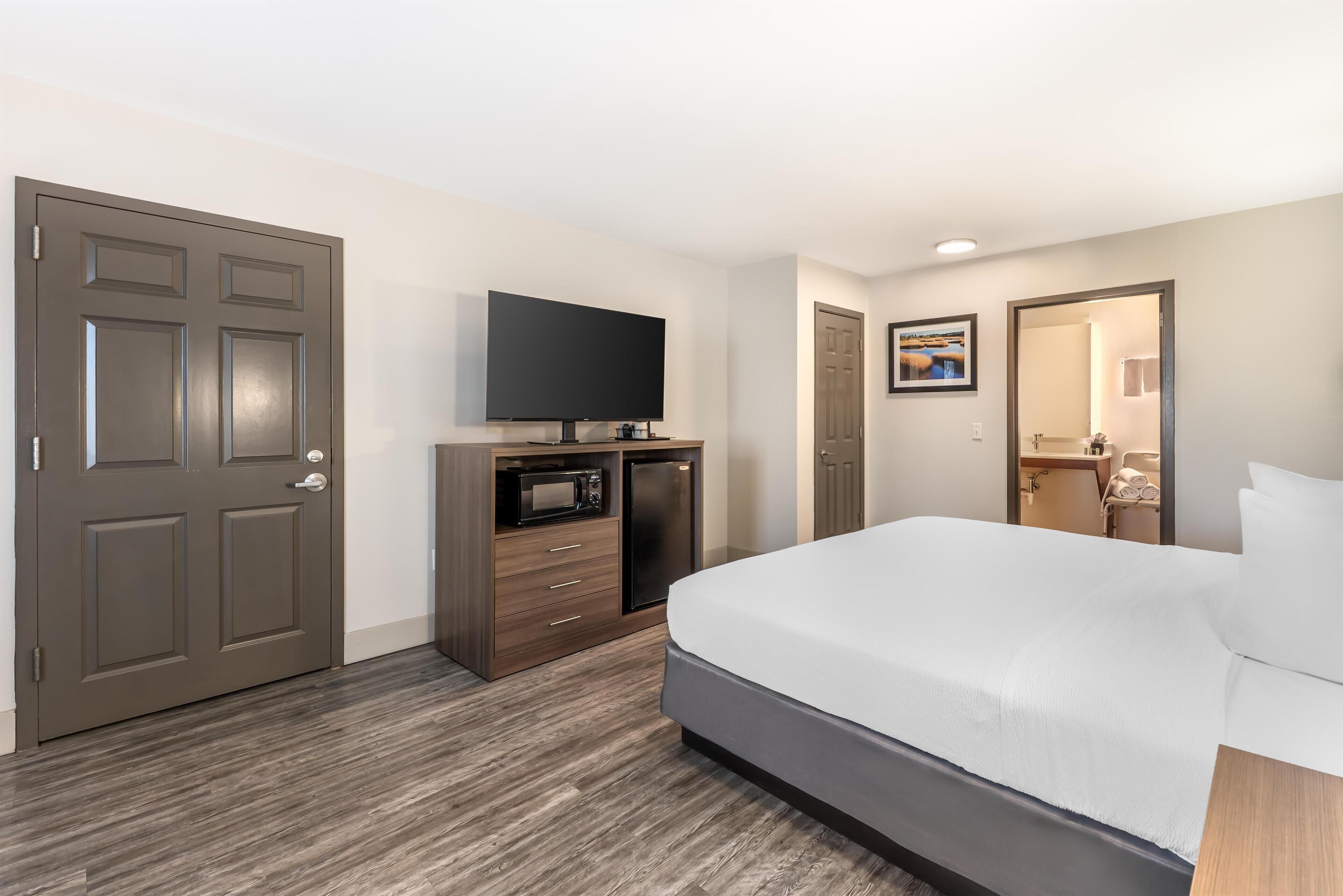 Une chambre d’hôtel équipée d’un lit, d’un téléviseur à écran plat, d’un four à micro-ondes et d’un petit réfrigérateur.
