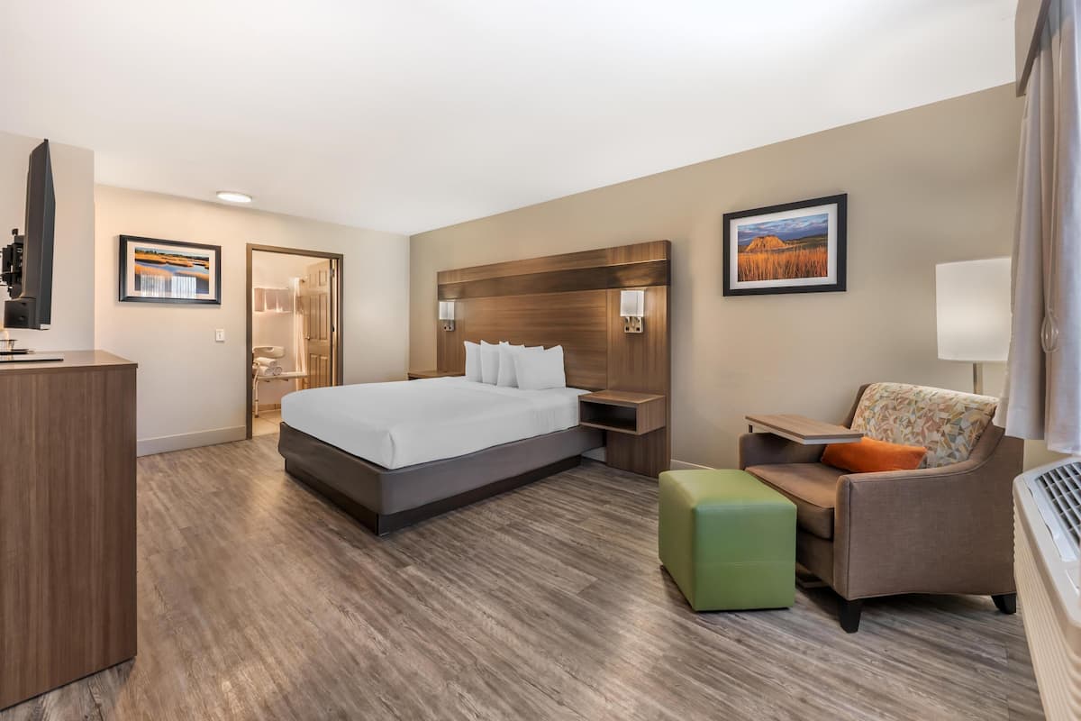A hotel room with a large bed, a desk, a chair, and a TV.
