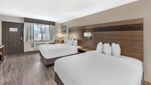 Une chambre d’hôtel avec deux lits, un bureau, une chaise, une fenêtre avec des rideaux, une lampe fixée au mur et un tableau.