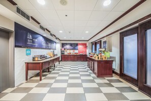A hotel lobby with a checkered floor, a bakery counter, and a juice bar.