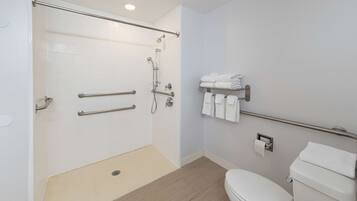 A modern bathroom with a walk-in shower, grab bars, a toilet, and a towel rack.