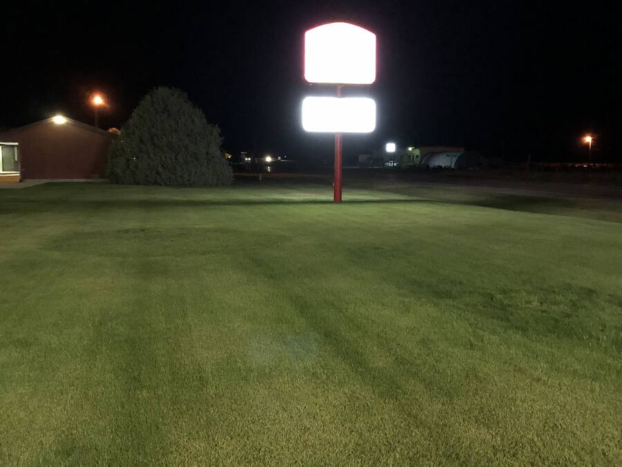 A well-lit sports field at night with a large illuminated sign.