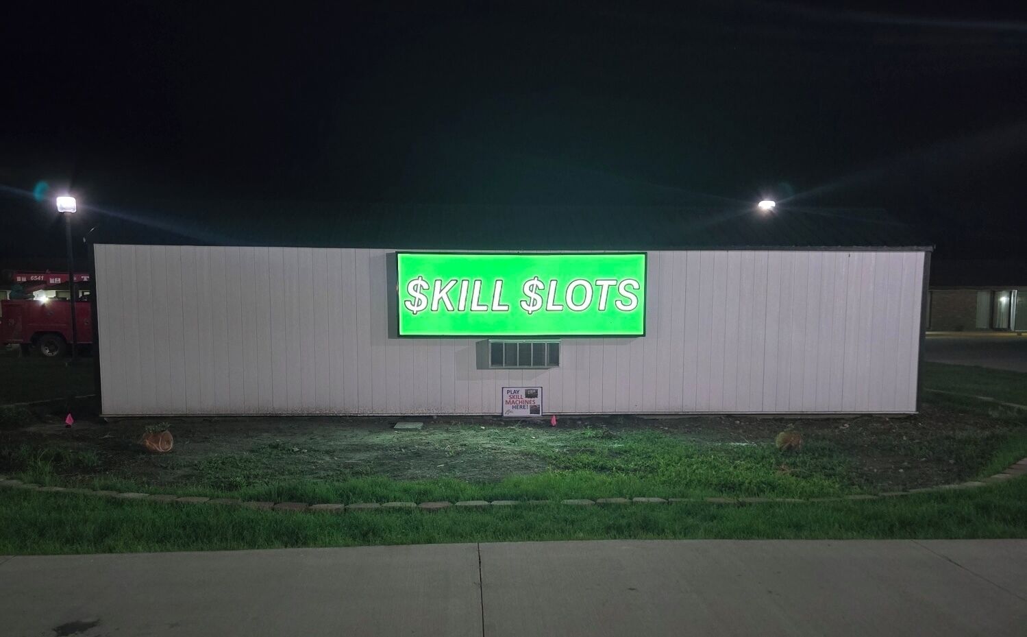 Un edificio con un letrero de neón que dice "SKILL LOTS" en la noche.