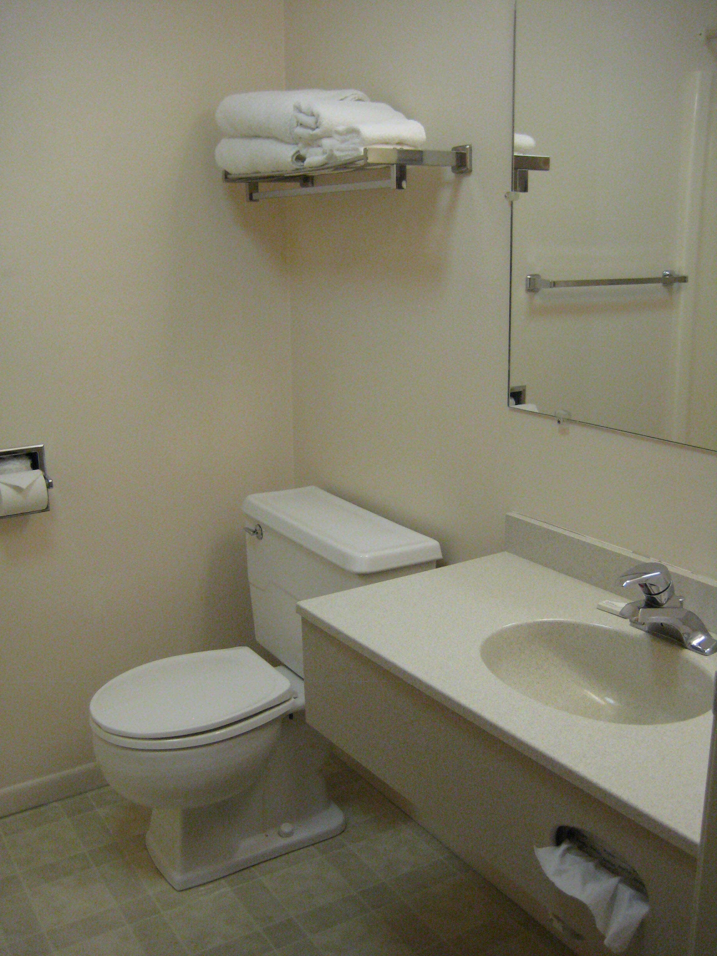 Un baño con inodoro, lavamanos y un perchero sobre el inodoro.