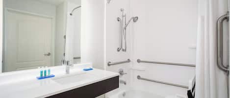 Une salle de bain avec une baignoire blanche, un lavabo double avec un plan de toilette foncé et un grand miroir.