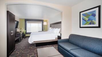 A hotel room with a bed, a sofa, a desk, and a television.