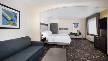 A hotel room with a bed, a sofa, a desk, and a TV.