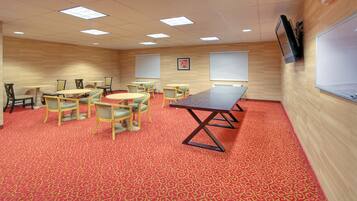 Une salle de conférence dotée d’un tapis rouge à motifs, de murs en bois et d’une grande table entourée de chaises.