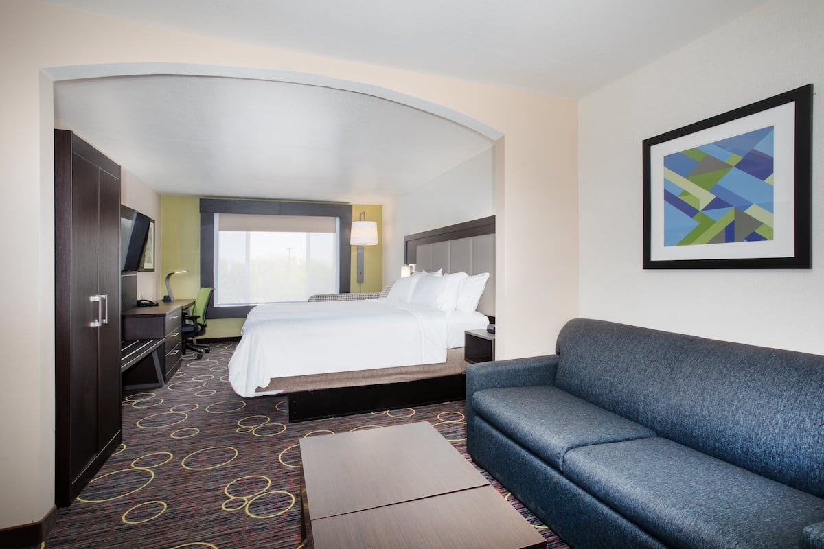 Ein Hotelzimmer mit Bett, Sofa, Schreibtisch und Fernseher.
