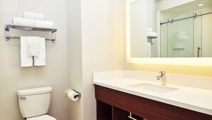 A bathroom with a toilet, a sink, a mirror, and a towel rack. - Holiday Inn Express & Suites Corona by IHG (Corona)