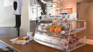 A breakfast counter with a hand sanitizer dispenser, a fruit display, and labeled food items. - Holiday Inn Express & Suites Corona by IHG (Corona)