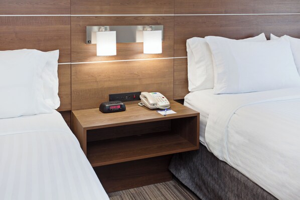 A hotel room with two beds, a wooden nightstand with a telephone and a digital clock, and wall-mounted lights. - Holiday Inn Express & Suites Corona by IHG (Corona)