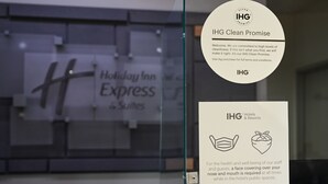A glass partition with a Holiday Inn Express sign and two IHG Clean Promise posters. - Holiday Inn Express & Suites Corona by IHG (Corona)