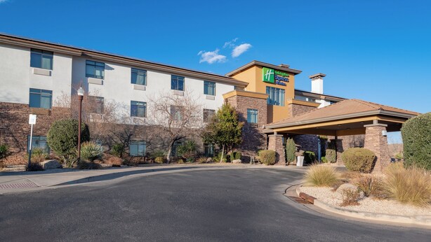A hotel with a modern design, featuring a mix of stone and stucco exterior, a covered entrance, and a clear sky.