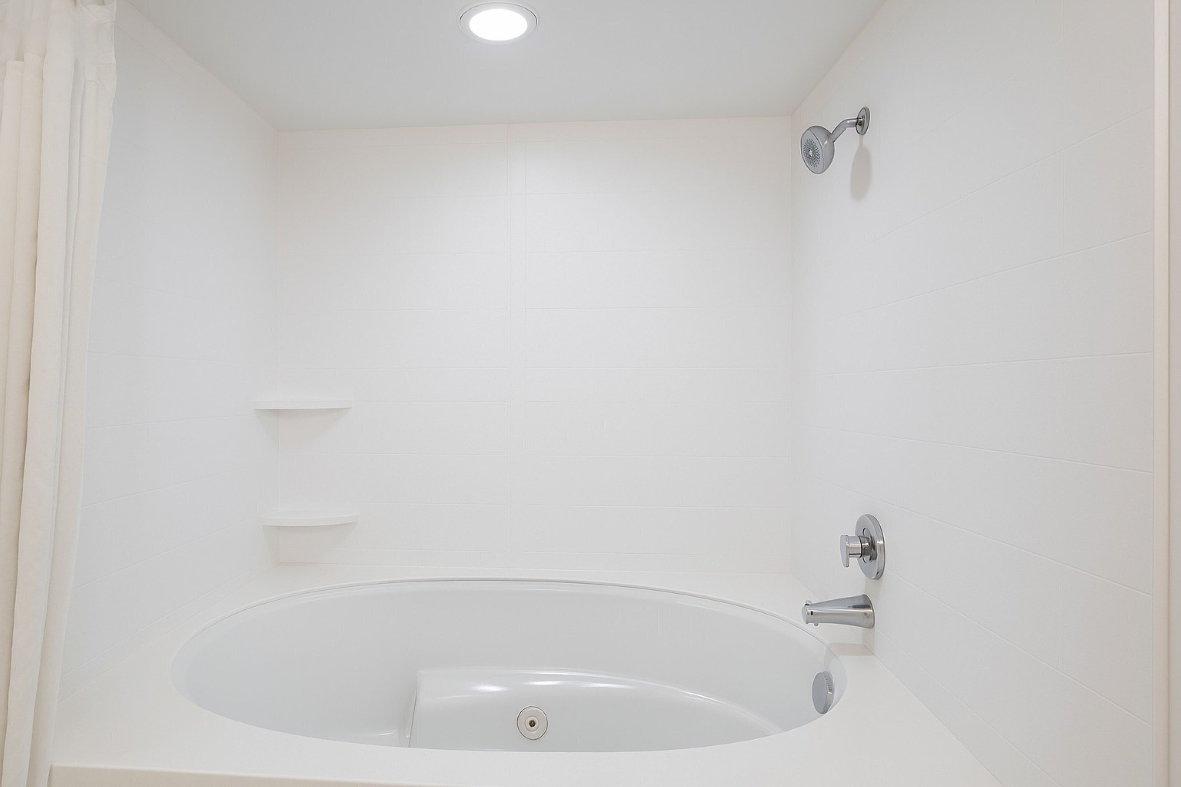 Un baño moderno con una bañera independiente, un cabezal de ducha y una lámpara en el techo.