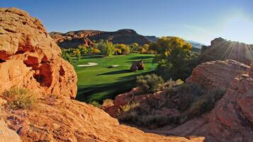 Un campo de golf con terreno rocoso y montañas a lo lejos.