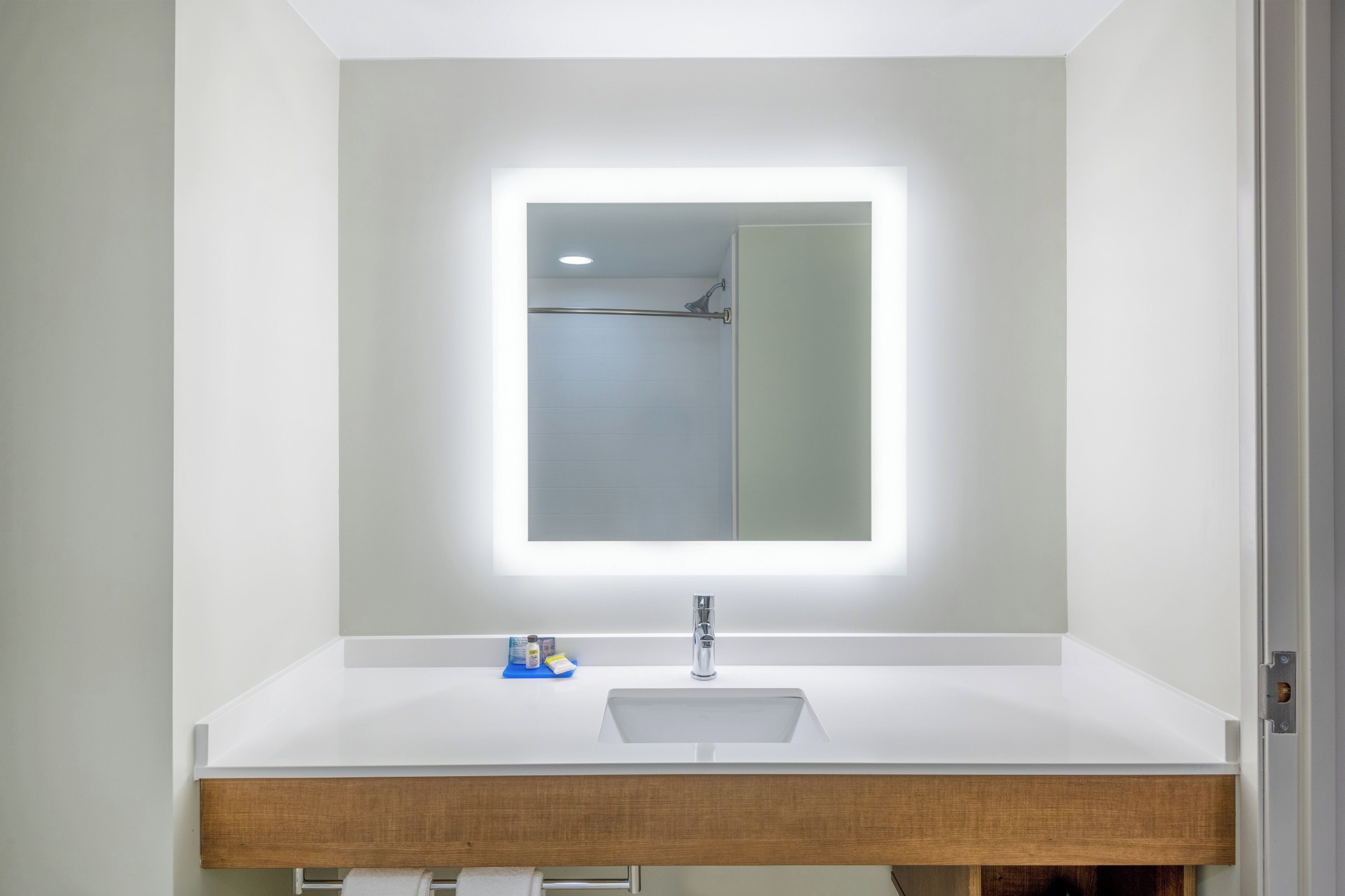 Un baño con lavamanos blanco, espejo y ducha.
