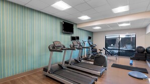 A gym with treadmills, exercise bikes, and weights.