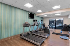 A gym with treadmills, exercise bikes, and weights.