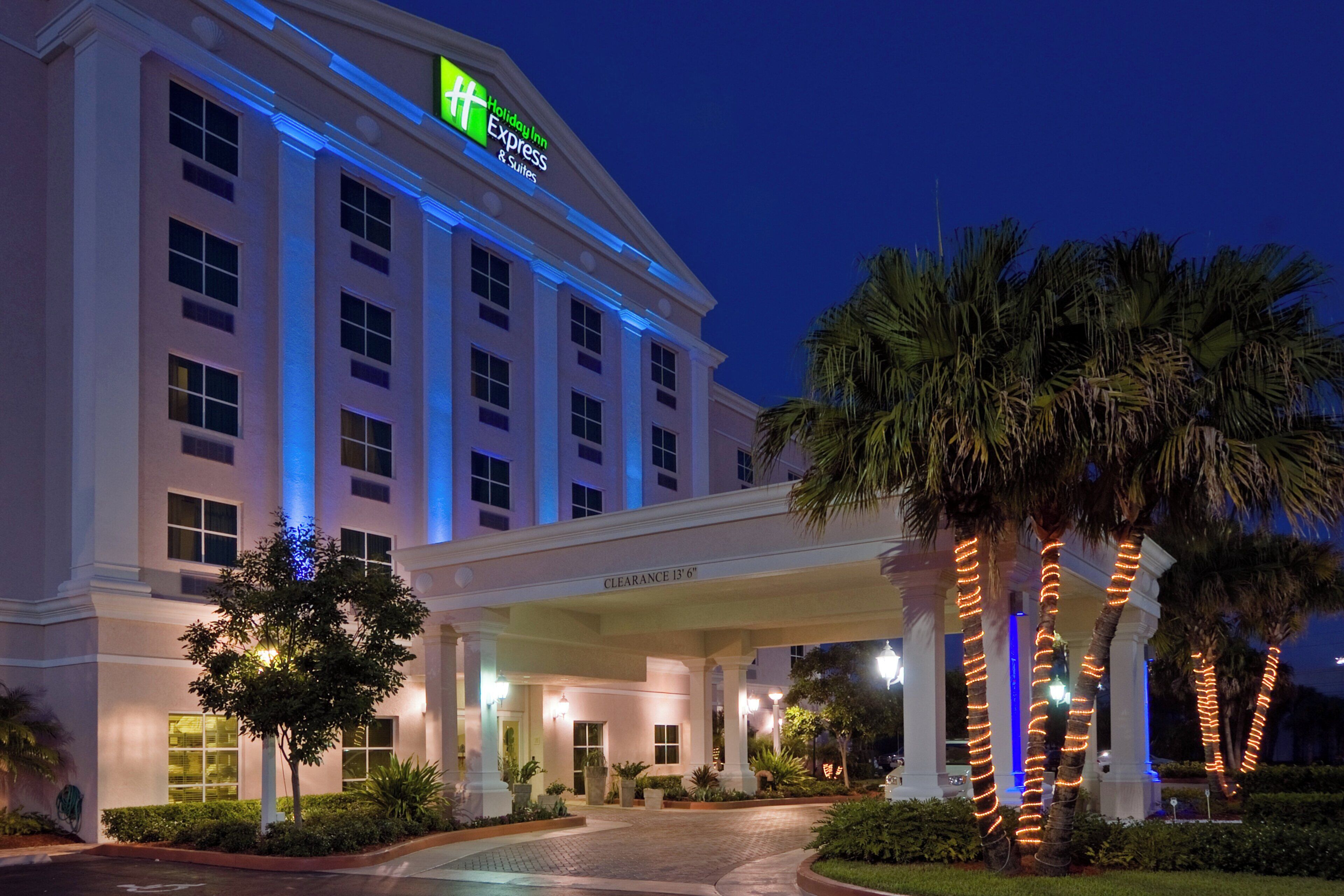 A Holiday Inn Express hotel with a clear entrance, palm trees, and a well-lit facade.