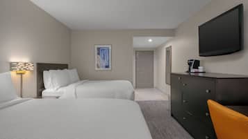 A hotel room with two beds, a desk, a television, and a door leading to another room.