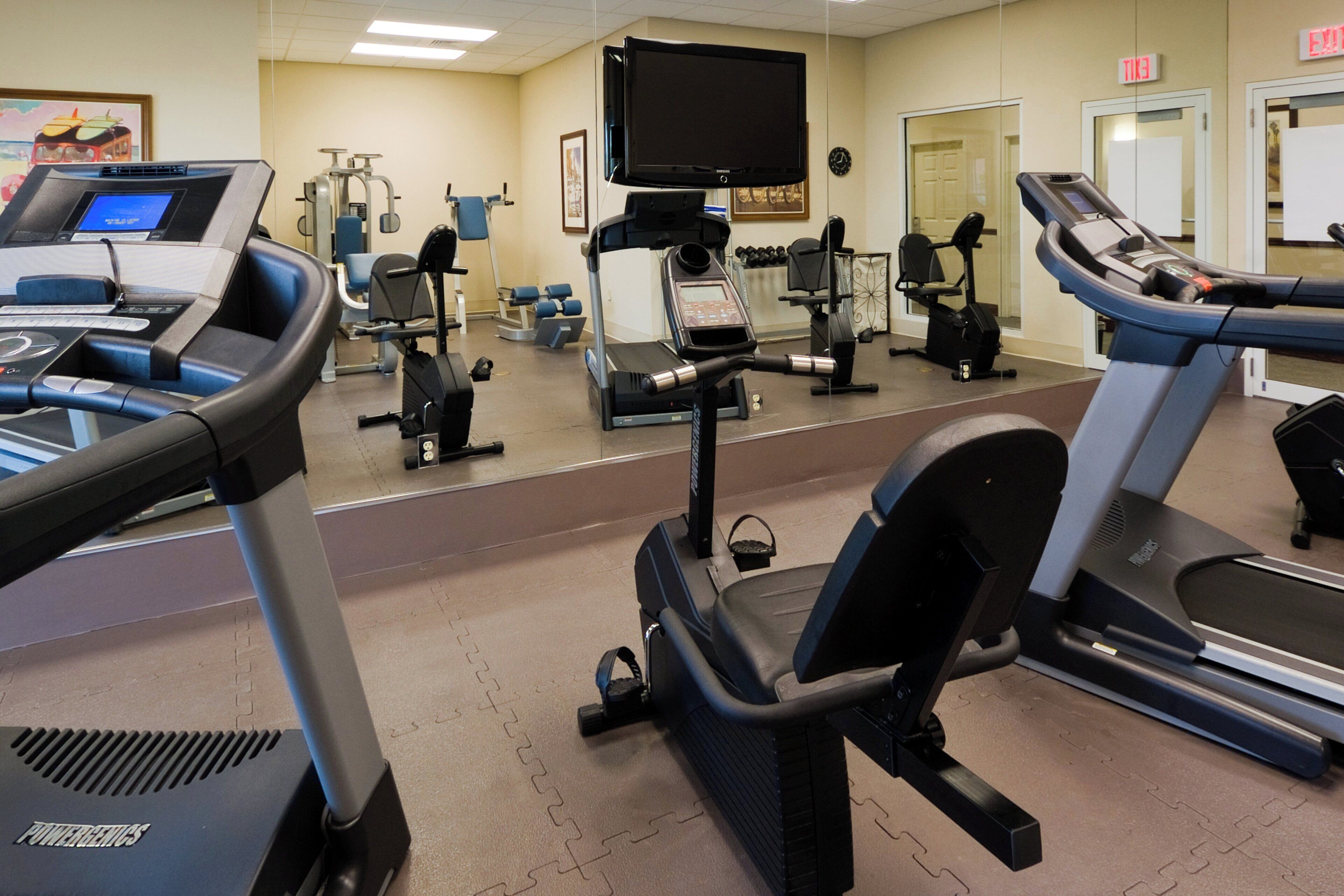 Ein Fitnessstudio mit verschiedenen Trainingsgeräten, darunter Laufbänder, Ergometer und Kraftgeräte.
