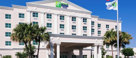 A large hotel building with a prominent entrance, palm trees, and an American flag.