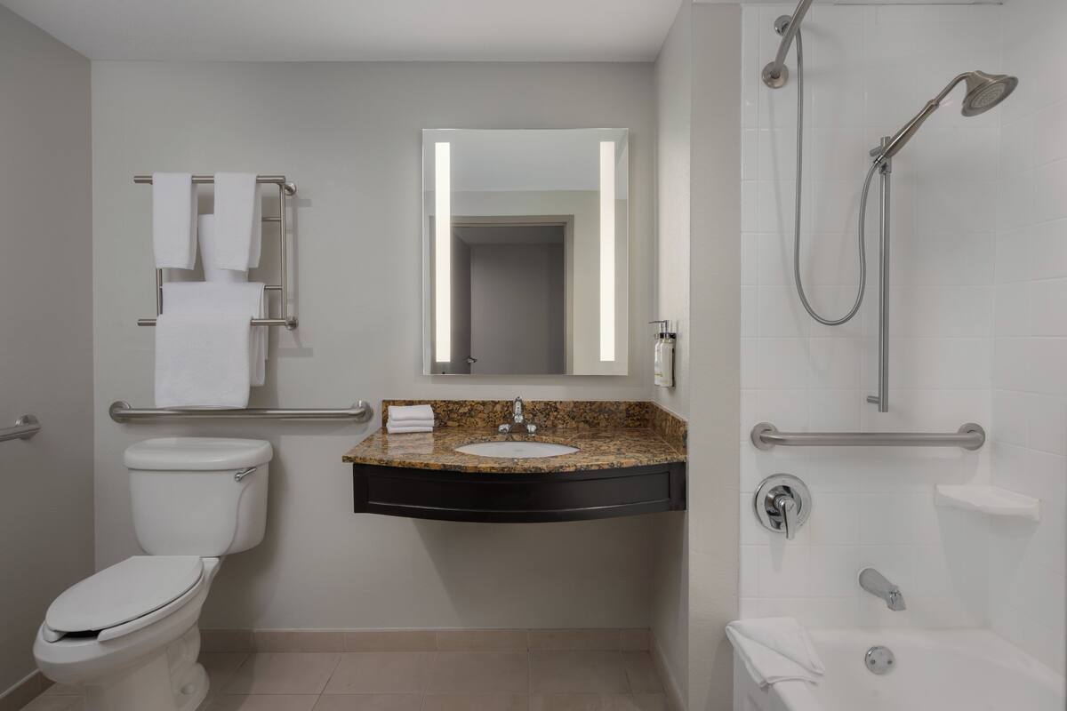 A modern bathroom with a toilet, sink, mirror, and shower.